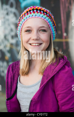 Ragazza che indossa un cappello a maglia di fronte a un muro con graffiti Foto Stock