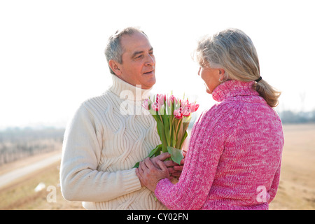 Senior uomo dando il suo partner un bouquet di tulipani Foto Stock