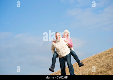 Senior uomo che porta il suo partner piggyback Foto Stock