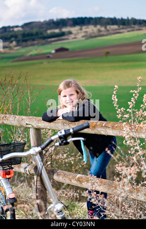 Ragazza con la bicicletta in parte anteriore del paesaggio rurale Foto Stock