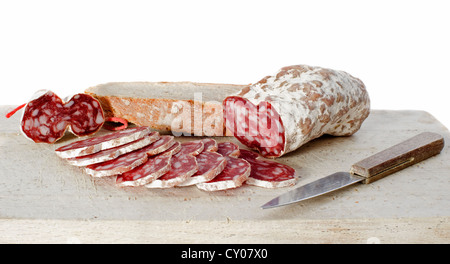 Fette di salsiccia francese sul bordo di taglio con il coltello nella parte anteriore del fondo bianco Foto Stock
