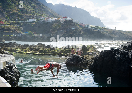 Giovane uomo saltare in acqua, piscine di acqua salata vicino a Garachico, Tenerife, Isole Canarie, Spagna, Europa Foto Stock
