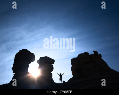 Silhouette di figura maschile in piedi sulla roccia e sunrise Foto Stock