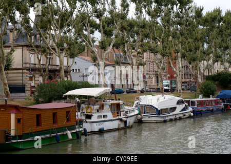 Lato Canale house barche e chiatte in Narbonne sul Canal de la Robine nel sud della Francia. Il canale è rivestito con Platani Foto Stock