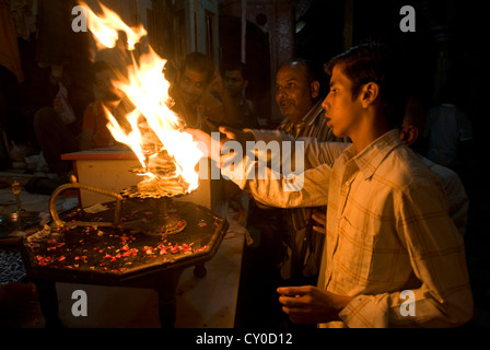 Per i fanatici indù passano le loro mani attraverso un rituale sacro fiamma ad Vishram ghat, Mathura, India Foto Stock