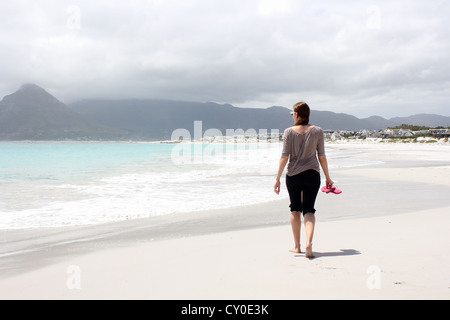 La donna a piedi lungo la spiaggia di Kommetjie con un imminente tempesta in background Foto Stock