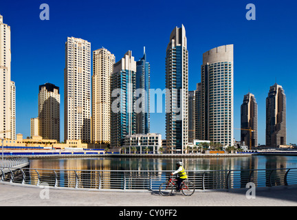 Un ciclista di cicli che la Marina a piedi che si affaccia sulla Marina di Dubai e JBR, EMIRATI ARABI UNITI Foto Stock