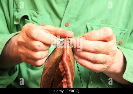 Julian Goodacre cornamuse maker Peeples in Scozia. Lavorando su un set di tubi, cucire il cuoio air bag, utilizzando una fascetta. Foto Stock