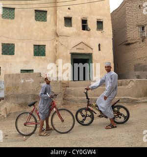 Due ragazzi in sella bici davanti alla residenza , Nizwa, Oman Foto Stock