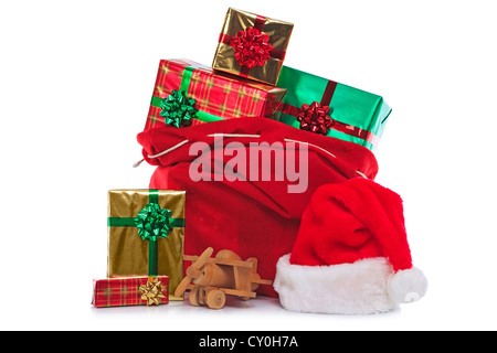 Foto di un rosso Berretto di Babbo Natale e il sacco pieno di regalo presenta e giocattoli, isolato su uno sfondo bianco. Foto Stock