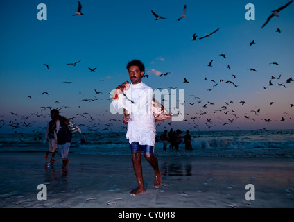 Uomo di ritorno dalla pesca e prendere i pesci Torna al crepuscolo, Salalah, Oman Foto Stock