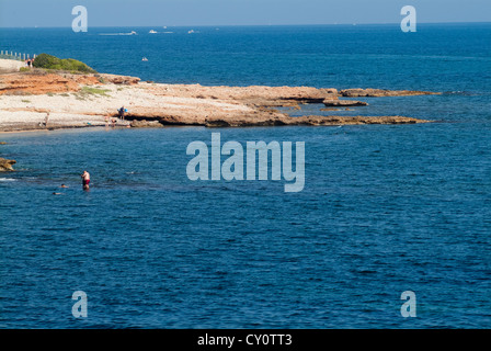 La gente sta facendo il bagno in una spiaggia rocciosa, Les Rotes, Denia, Capo di San Antonio, provincia di Alicante, Spagna, Europa Foto Stock