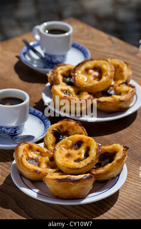 Pasteis de nata o Pasteis de Belem; crema pasticcera crostate, su una tabella di caffè all'aperto con bica caffè; Belém, Lisbona, Portogallo Foto Stock