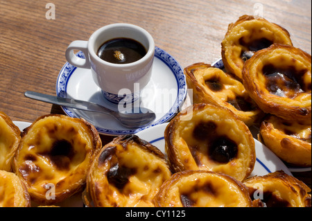 Pasteis de nata o Pasteis de Belem; crema pasticcera crostate, su una tabella di caffè all'aperto con un bica caffè; Belém, Lisbona, Portogallo Foto Stock