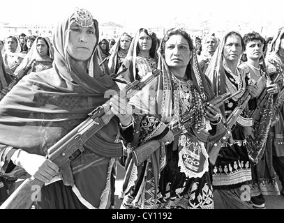 Le donne afghane villaggio le forze di difesa nel tradizionale costume tribale trasportare AK sovietica-47's durante una parata per segnare il decimo anniversario della rivoluzione comunista Aprile 26, 1988 a Kabul, Afghanistan. Foto Stock