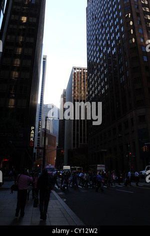 Sfumatura scura vicolo urbano ritratto persone attraversando Water Street a Wall Street, sotto vetro soleggiata muratura grattacieli di New York Foto Stock