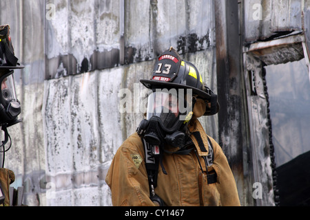 Una donna pompiere sulla scena di un incendio in un edificio industriale Foto Stock