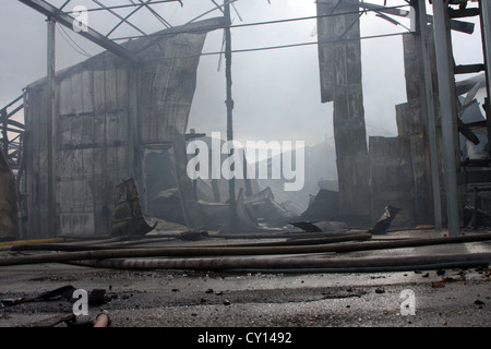 La scena di fuoco di un edificio industriale in cui il tetto è crollato Foto Stock