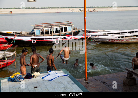 Giovani uomini saltando nel fiume Gange a Varanasi, India Foto Stock