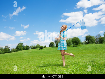 Bella ragazza con butterfly net camminando sul prato verde Foto Stock