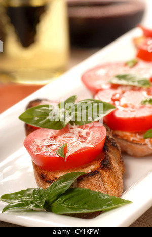 Deliziose bruschette con pomodoro a fette, origano fresco servito su un piatto bianco Foto Stock