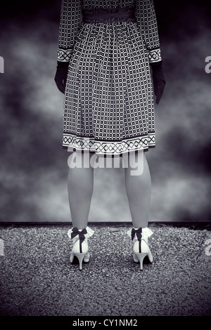 Una donna in bianco e nero il vestito è in piedi sul bordo di un tetto Foto Stock