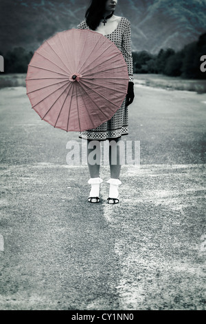 Una donna in bianco e nero vestito con un ombrello rosso Foto Stock