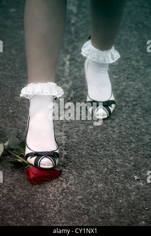 I piedi di una donna sono il rafforzamento su una rosa rossa Foto Stock