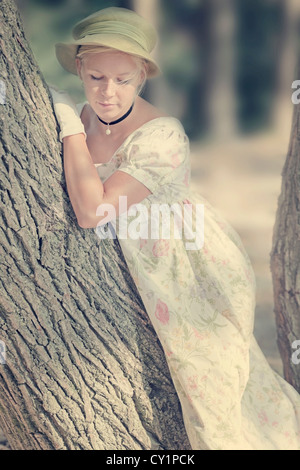 Una donna con un abito di loral è appoggiato a un albero Foto Stock