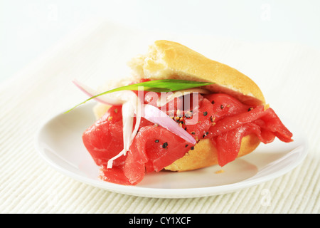 Baguette con sottili fette di carne di manzo crudo Foto Stock