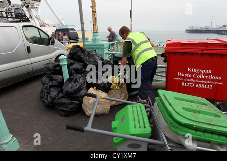 Un Consiglio di collettore di rifiutare il prelievo di tutti i rifiuti dalla Spiaggia di Brighton vicino a Brighton (Palazzo) Pier, East Sussex, Regno Unito. Foto Stock