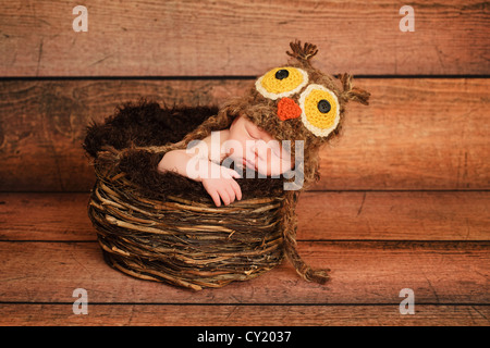 1 settimana vecchia ragazza neonata indossando un gufo marrone cappello e dormire in un nido. Foto Stock