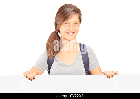 Scuola ragazza con zaino in posa dietro il pannello bianco isolato su sfondo bianco Foto Stock