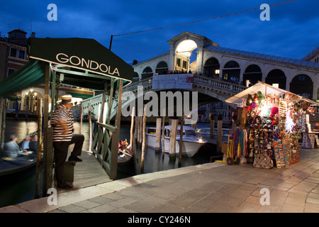 Un gondoliere in attesa per i clienti di fronte al Ponte di Rialto di notte, Grand Canal, Venezia Foto Stock