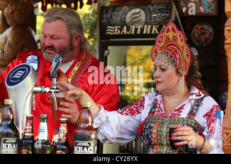 Durante un festival popolo ucraino in costumi tradizionali che serve birra dall'Europa Orientale dietro una bevanda stand. Foto Stock