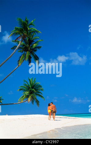 Giovane a piedi e baciare sotto le palme sulla sabbia bianca di isola tropicale spiaggia delle Maldive Foto Stock