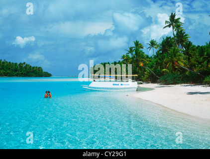 La barca turistica e giovane ancorato in aqua acque del Pacifico del Sud a un piede isola in Laguna Aitutaki nelle Isole Cook Foto Stock