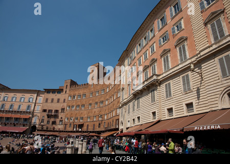 Piazza del Campo a Siena, Italia. Gli edifici storici che circondano la piazza in pendenza, affollato di gente e di turisti. Foto Stock