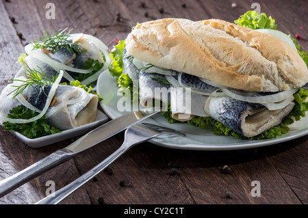 Filetto di aringa su una baguette contro lo sfondo di legno Foto Stock