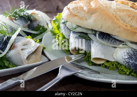 Filetto di aringa su una baguette contro lo sfondo di legno Foto Stock