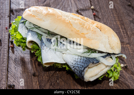 Filetto di aringa su una baguette contro lo sfondo di legno Foto Stock