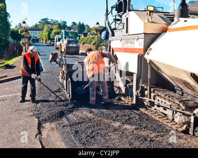 Operai diffusione di tarmac / asfalto macchina di stendimento in funzionamento - Francia. Foto Stock