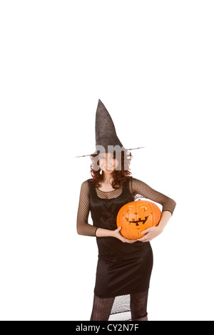 Ritratto di giovane donna ispanica in nero Halloween costume (fishnet abito) azienda zucca intagliata (jack-o-lantern) in mani Foto Stock