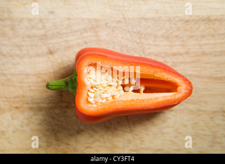 Sezione trasversale di un peperone rosso, su un tagliere di legno. Foto Stock