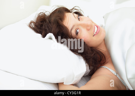 Bella donna sdraiata sul divano e sorridente Foto Stock