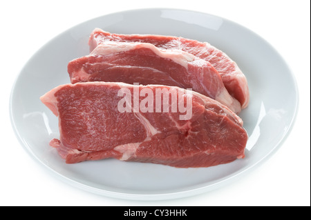 Raw gamba Di agnello bistecche di carne cruda su una piastra isolata su uno sfondo bianco Foto Stock