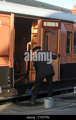 Appassionato di rampa di pulizia della piattaforma e carrozze ferroviarie a Sheffield Park Station sulla linea Bluebell SUSSEX REGNO UNITO Foto Stock