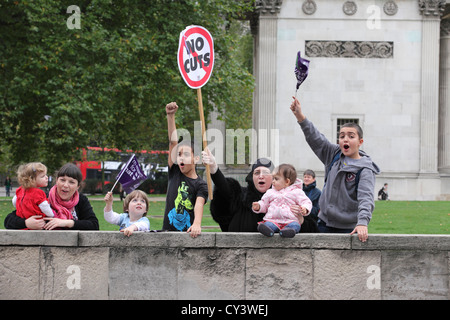 Niente tagli giovane famiglia sventolando il tifo guardando il supporto di un futuro che funziona in segno di protesta a Londra, Regno Unito Foto Stock