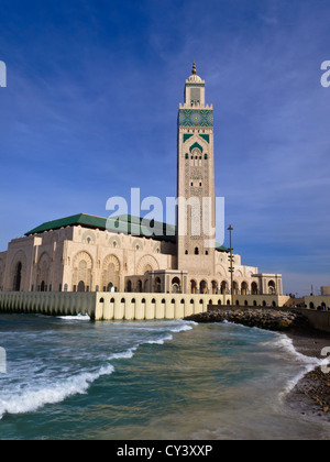 Vista di white moschea di Hassan II e minareto di Casablanca, Marocco con onde che si infrangono le sue pareti di mare Foto Stock