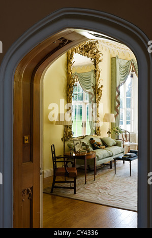 Vista attraverso il portale ad arco in un disegno di colore giallo-room con antichi gilt incorniciato specchio francese Foto Stock